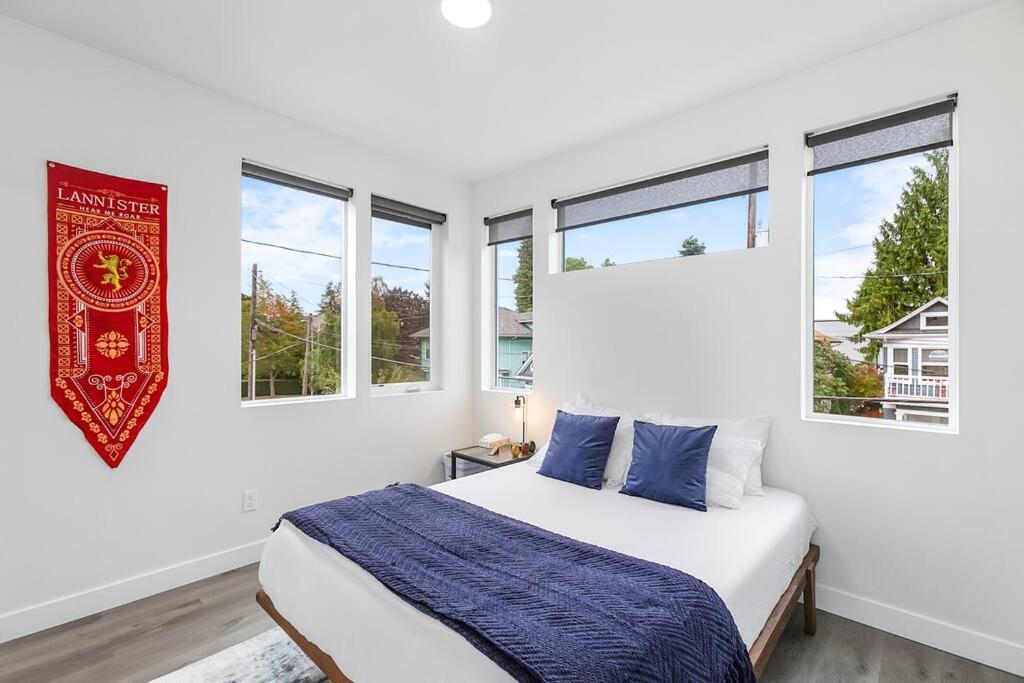 Dormitorio blanco con cama y ventanas en Martell's Sunspear Sweet Suite en Seattle
