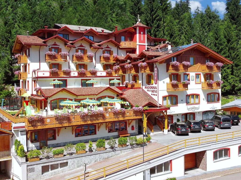a hotel with balconies and cars parked in front of it at Hotel Madonna delle Nevi in Folgarida