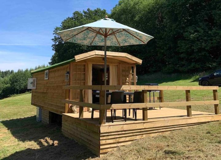 a wooden house with an umbrella on top of it at Jabba The Hut in Sturminster Marshall