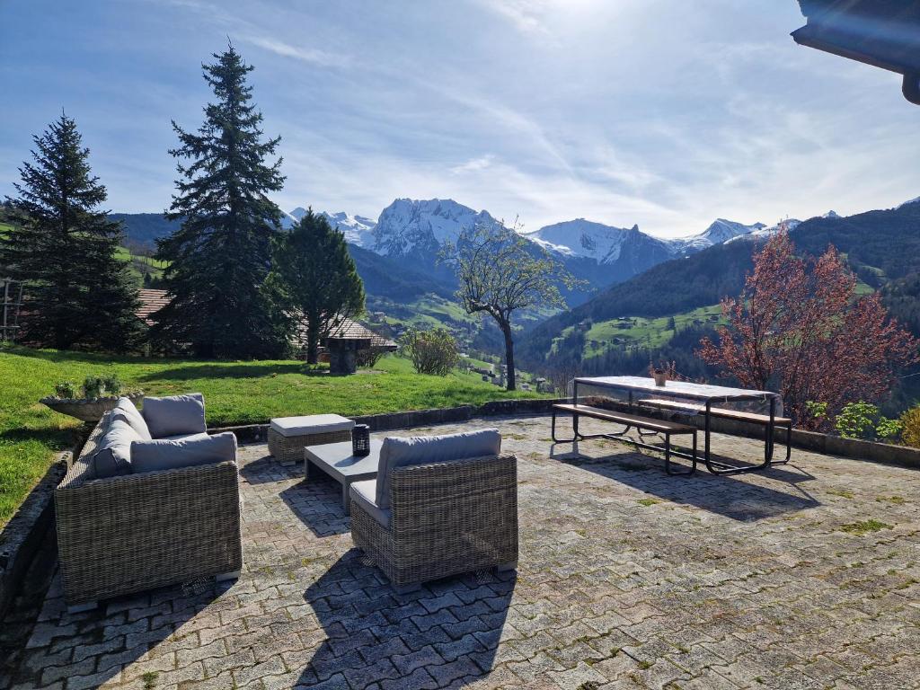 a patio with two chairs and a table and mountains at Chalet de Manigod in Manigod