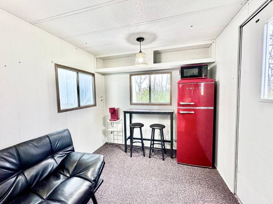 a living room with a red refrigerator and a table at Trestle Creeks Farmhouse Fort Tiny House in Bloomington