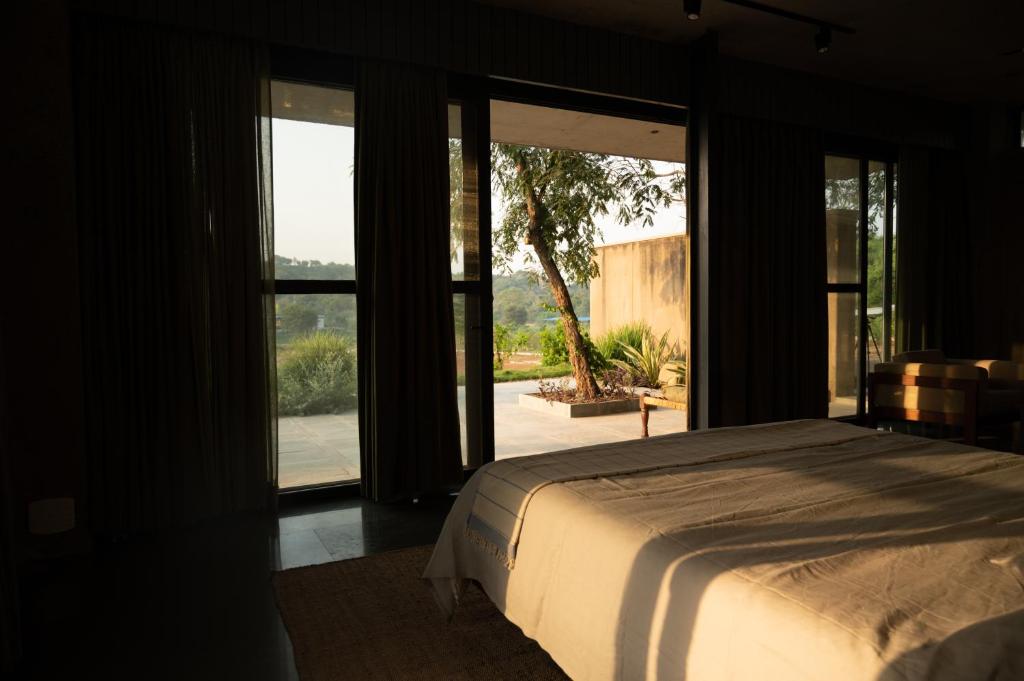 a bedroom with a bed and sliding glass doors at Jaadooghar Stays, Earth Friendly Stay, Chandigarh in Chandīgarh