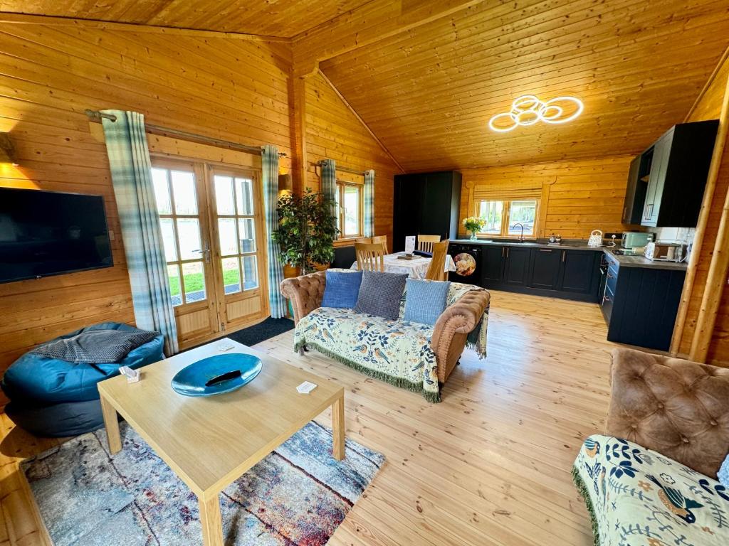 ein Wohnzimmer mit einem Sofa und einem Tisch in der Unterkunft Heron Lodge, Lake Pochard in South Cerney