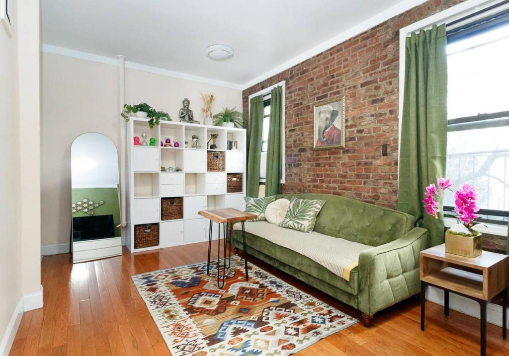 uma sala de estar com um sofá verde e uma parede de tijolos em Spacious 1BR Apartment em Nova York