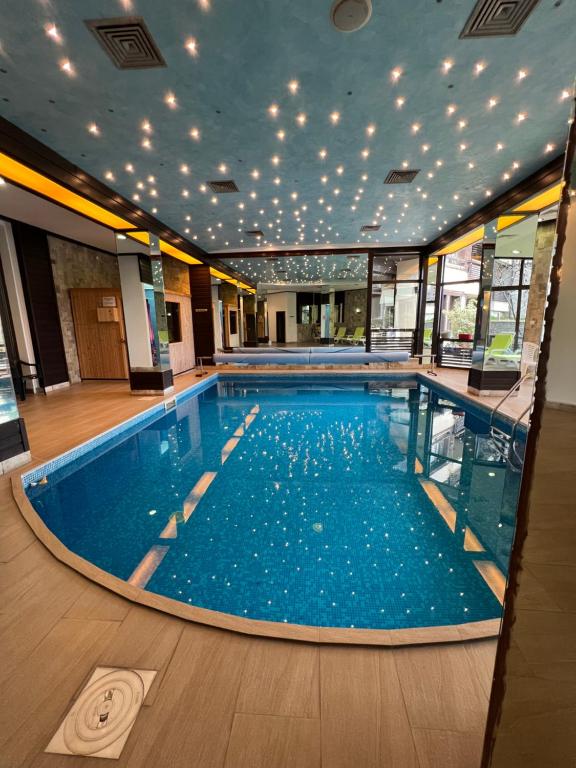 a large swimming pool with blue water in a building at Luxury Studio in Alpinе Lodge with SPA in Bansko