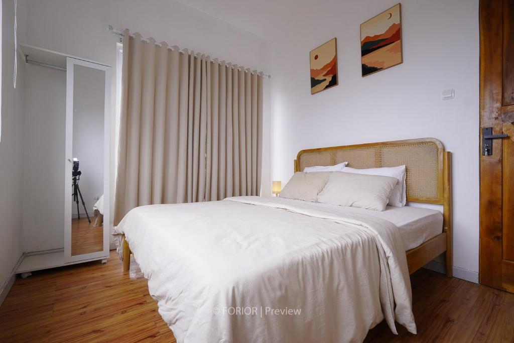 1 dormitorio con 1 cama grande con sábanas blancas en RUMAH BIRU en Bandung