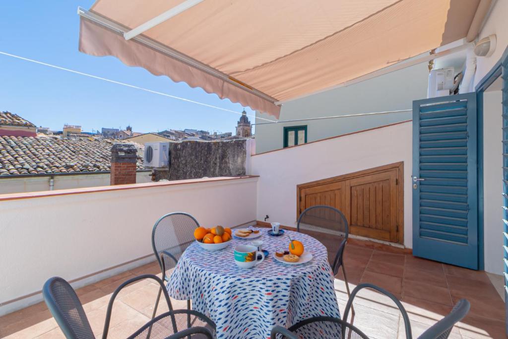 a table on a balcony with a table and chairs at Case Spazioscena - Tàlia in Castelbuono