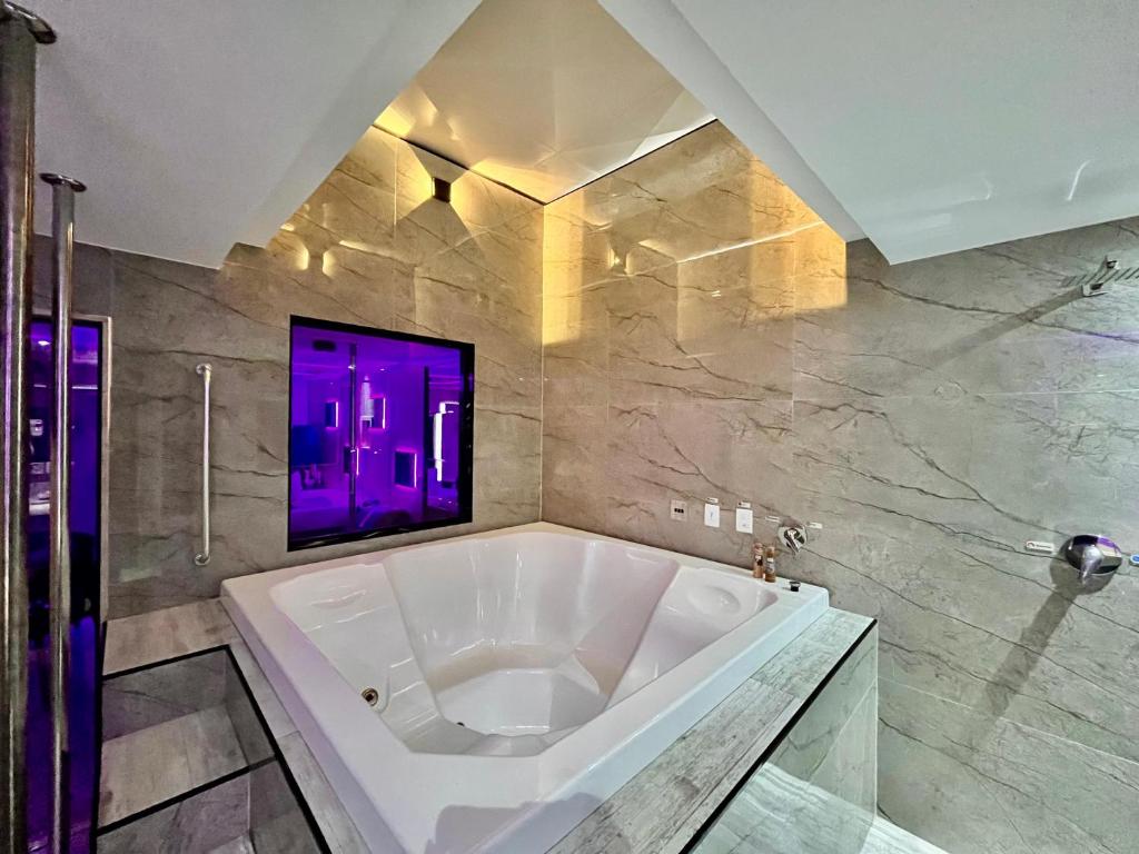La salle de bains est pourvue d'une grande baignoire blanche et d'un éclairage violet. dans l'établissement Cassino Motel 6, à Santo André