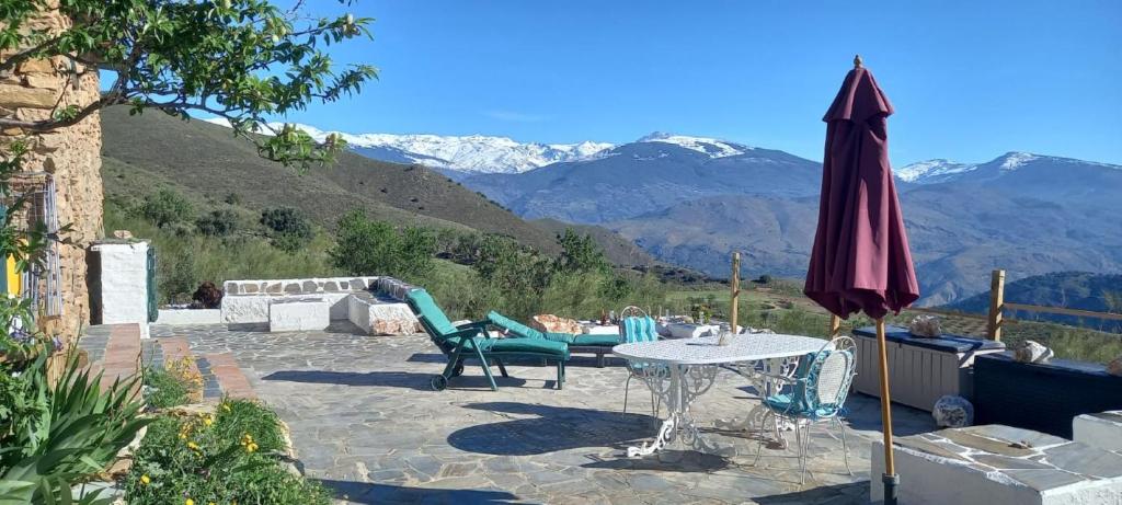 um pátio com um guarda-sol, uma mesa e cadeiras em Cortijo La Vista em Órgiva