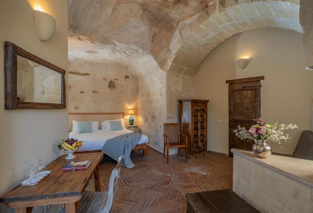 a bedroom with a bed and a table at Locanda Di San Martino Hotel & Thermae Romanae in Matera