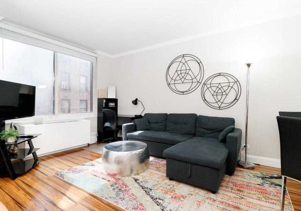 ein Wohnzimmer mit einem Sofa und einem TV in der Unterkunft Lovely Studio Apartment in NYC in New York