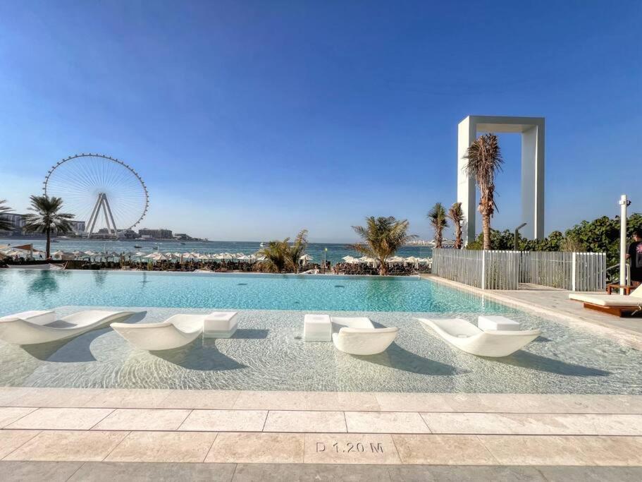 a swimming pool with white chairs and a ferris wheel at Fantastic and Rare 4BR+maid's in JBR Walk in Dubai