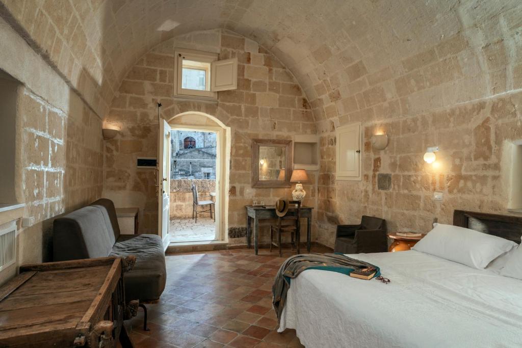 a bedroom with a bed and a table in a room at Locanda Di San Martino Hotel & Thermae Romanae in Matera