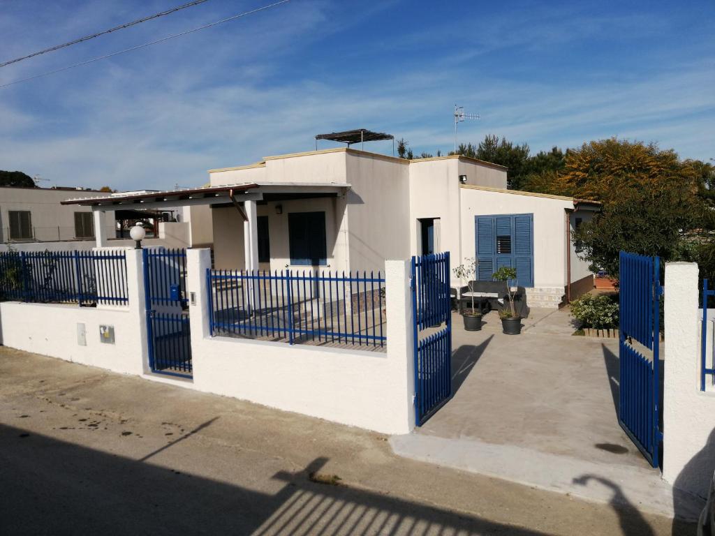 a white house with blue gates in front of it at Villa Sunshine in Triscina