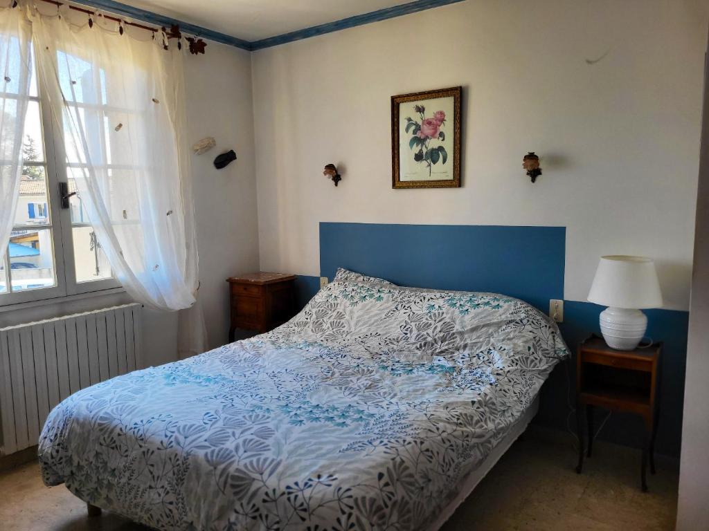 een slaapkamer met een blauw en wit bed en een raam bij Villa de 3 chambres avec piscine privee jardin clos et wifi a Aubignan in Aubignan