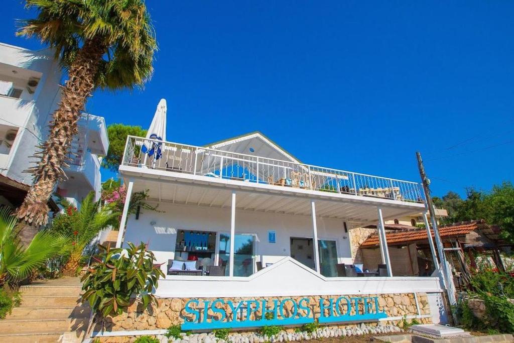 a white house with a balcony and a palm tree at Sisyphos Hotel in Gelemiş