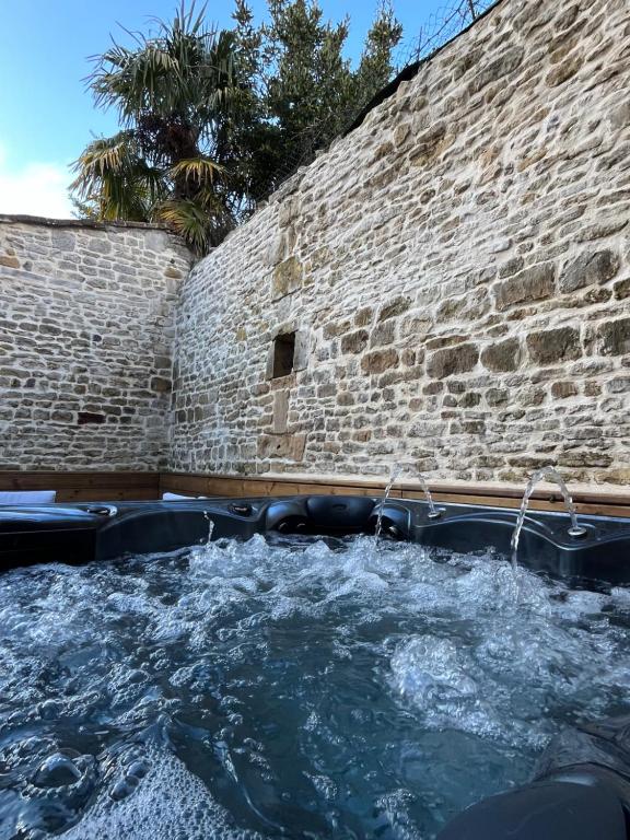 bañera de hidromasaje con agua en una pared de ladrillo en Maison en pierre avec jacuzzi, en Caen