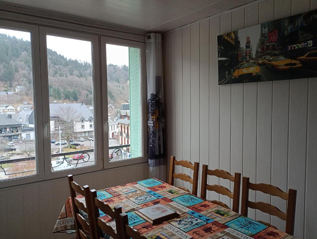 ein Esszimmer mit einem Tisch, 2 Stühlen und einem Fenster in der Unterkunft Mont Dore/Sancy 6 personnes emplacement privilégié in Le Mont-Dore