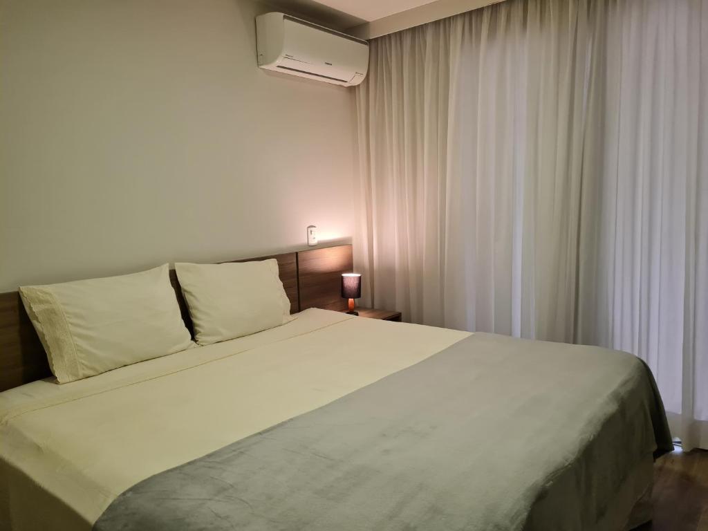 Un dormitorio con una gran cama blanca y una ventana en Suíte Luxo Via Premiere, en Río de Janeiro