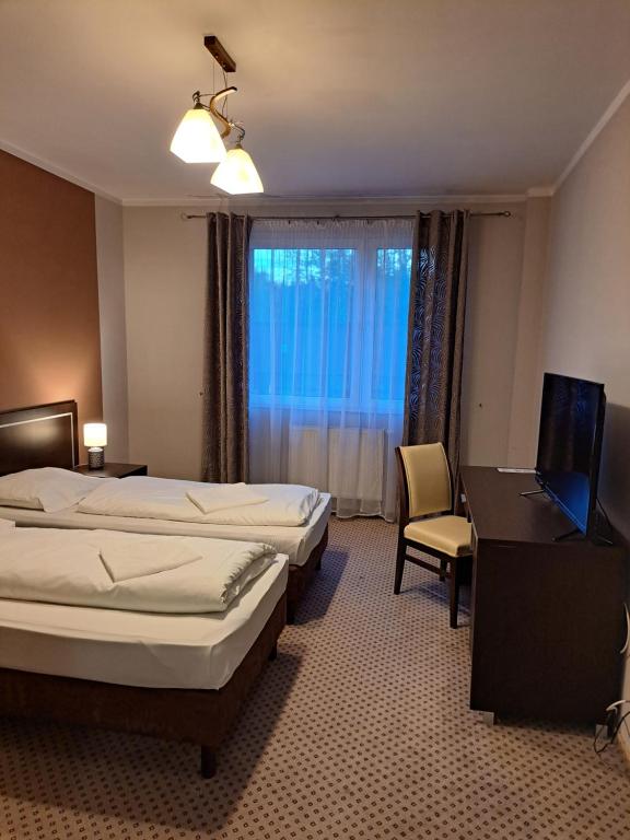 um quarto de hotel com 2 camas, uma secretária e um computador portátil em Trojak em Mysłowice