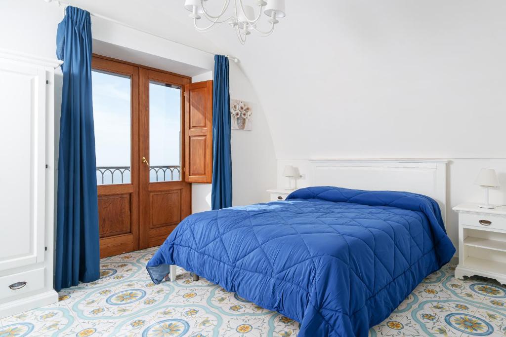 Un dormitorio con una cama azul y una ventana en Villa Prota, en Vico Equense