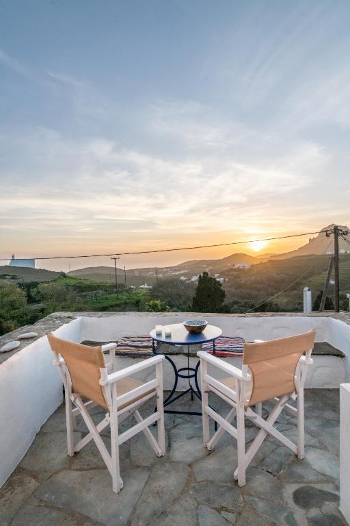 a patio with a table and two chairs and the sunset at Tinos Sunset Villa in Kékhros