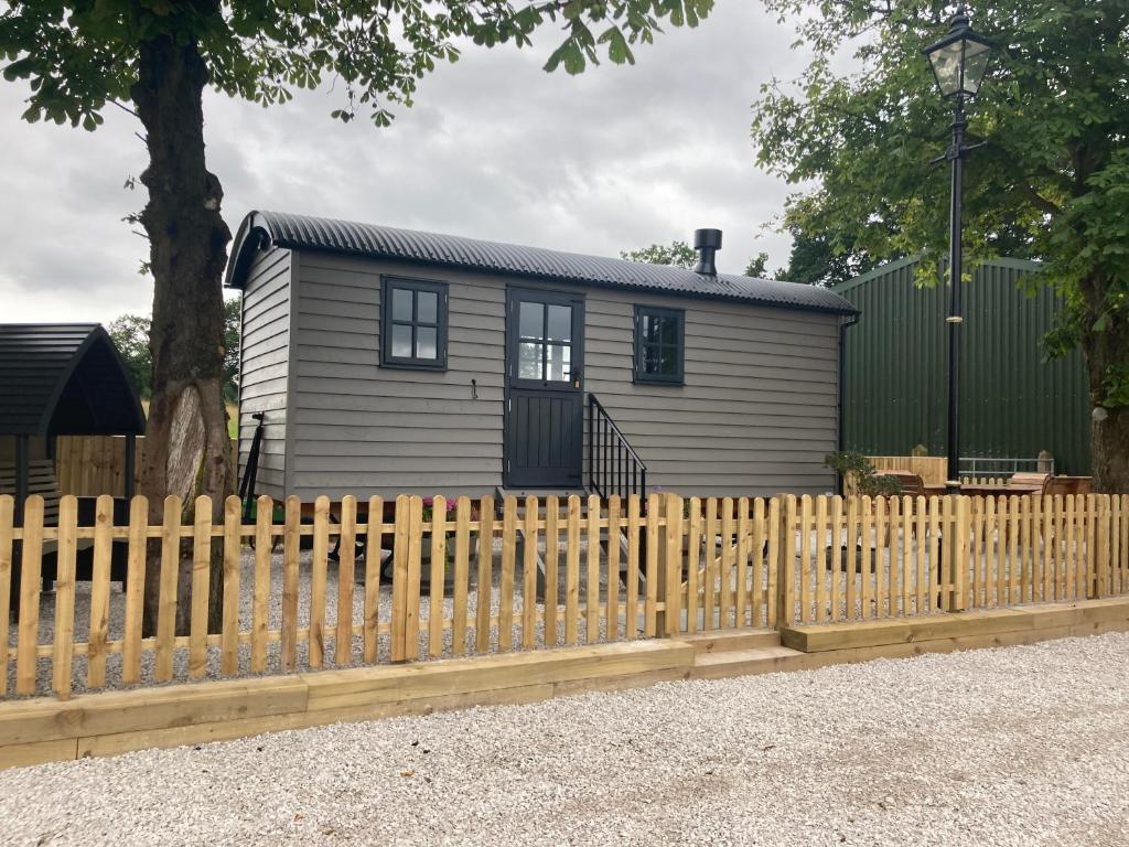 une petite maison derrière une clôture en bois dans l'établissement Owls Retreat, Meadowview House, à Stoke-on-Trent