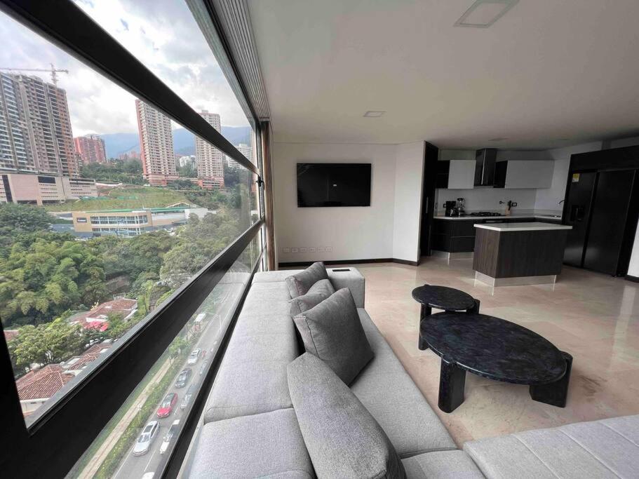 ein Wohnzimmer mit einem Sofa und einem großen Fenster in der Unterkunft 902 luxury apartment in heart of El Poblado! in Medellín