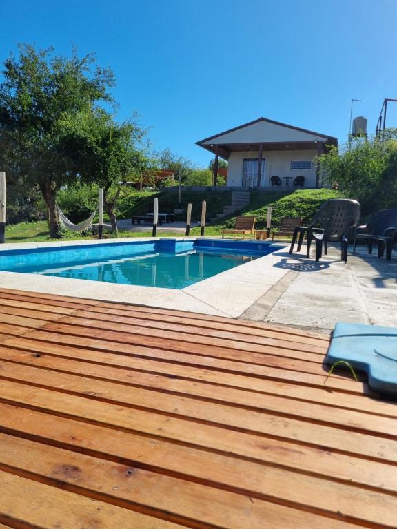 a swimming pool with a wooden deck next to a house at Terrazas de Estancia in Villa Carlos Paz