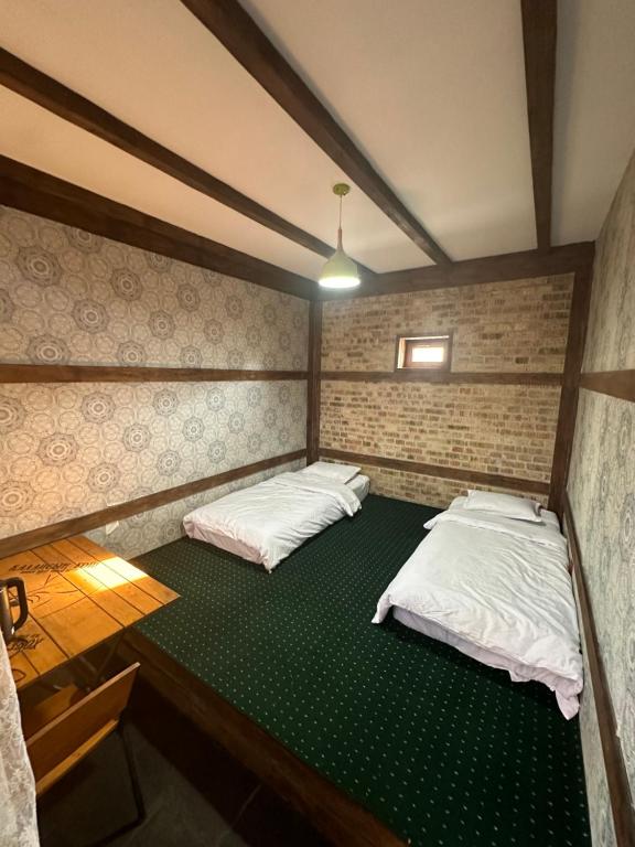 2 camas en una habitación con suelo verde en 阿拉木图市和平民宿, en Kalkaman