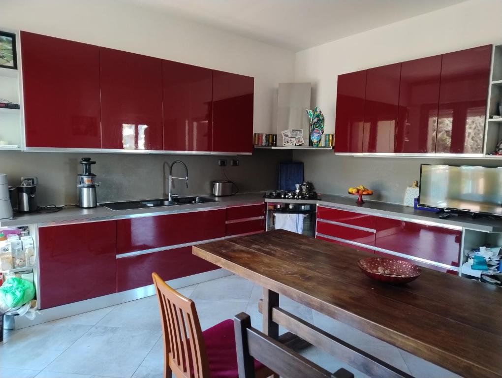 a kitchen with red cabinets and a wooden table at 5 Terre Italian Delight Red in La Spezia