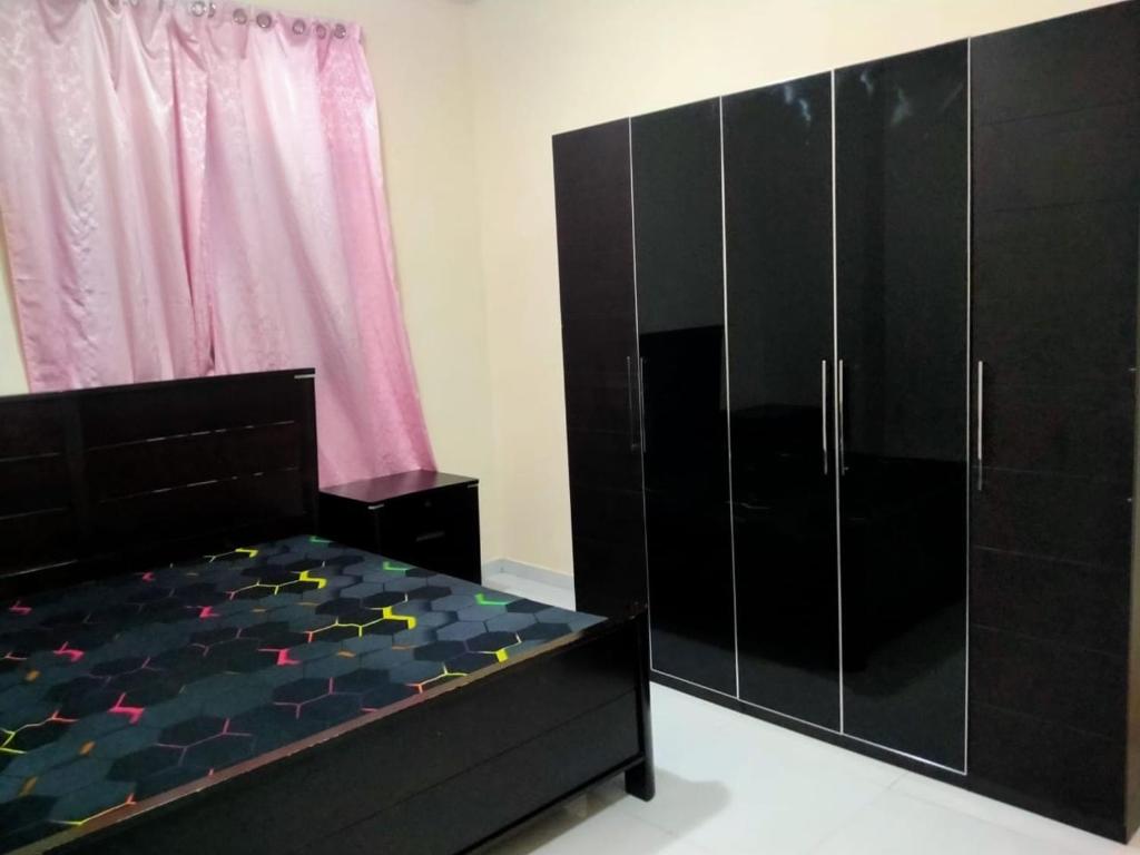 a bedroom with a black bed and a black cabinet at 1 BHK Fully Furnished Flat in Sharjah