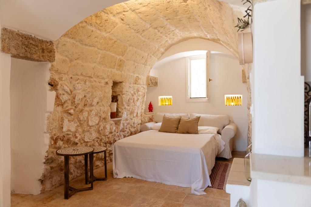 une chambre avec un lit et un mur en pierre dans l'établissement Tenuta Lavati, Santa Maria di Leuca, à Castrignano del Capo