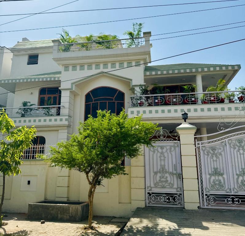 een wit huis met een boom ervoor bij Riya Villa (Kaashi Flora Unit) in Varanasi