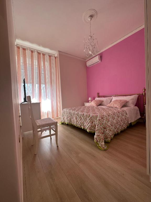 una camera da letto con pareti rosa, un letto e una sedia di Casa Rusenè: Herculaneum Domus a Ercolano