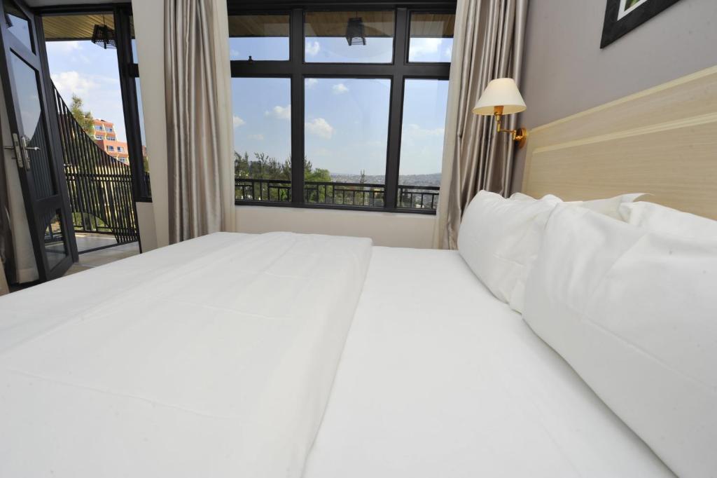 een slaapkamer met een groot wit bed en een raam bij Gloria Hotel in Kigali