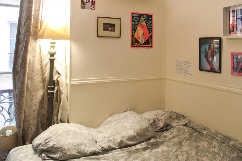 a bed in a room with a lamp and pictures on the wall at Apartment near the Marais in Paris
