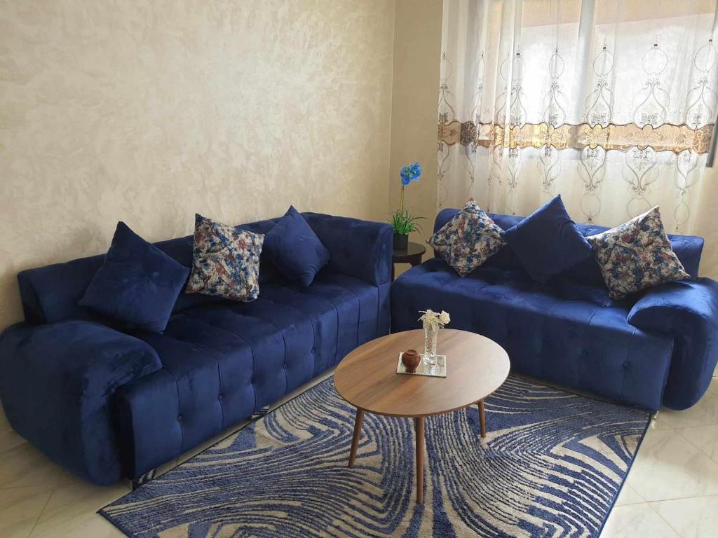 Appartement Dar Meknès في مكناس: غرفة معيشة مع أريكة زرقاء وطاولة