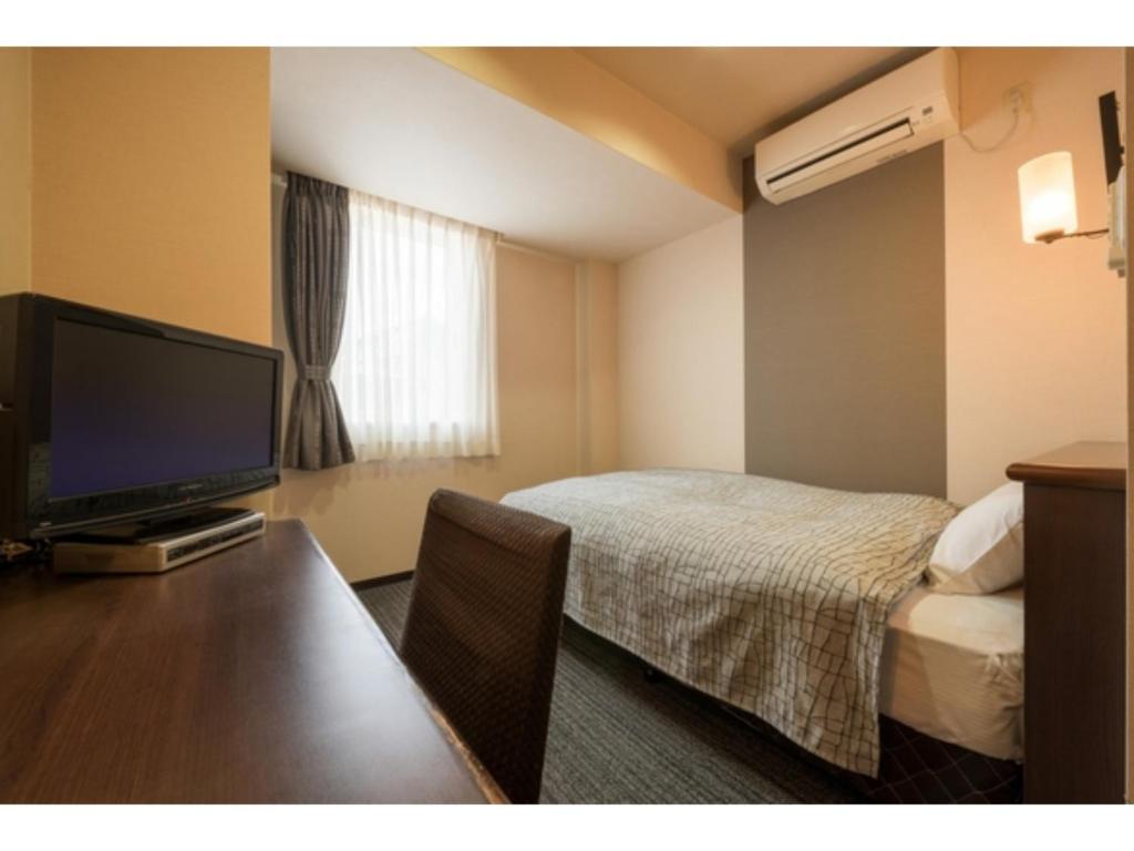 um quarto de hotel com uma cama e uma televisão de ecrã plano em Towada City Hotel - Vacation STAY 47280v em Towada