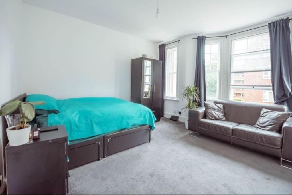 a bedroom with a green bed and a couch at Great Flat Close to Edgware Road in London