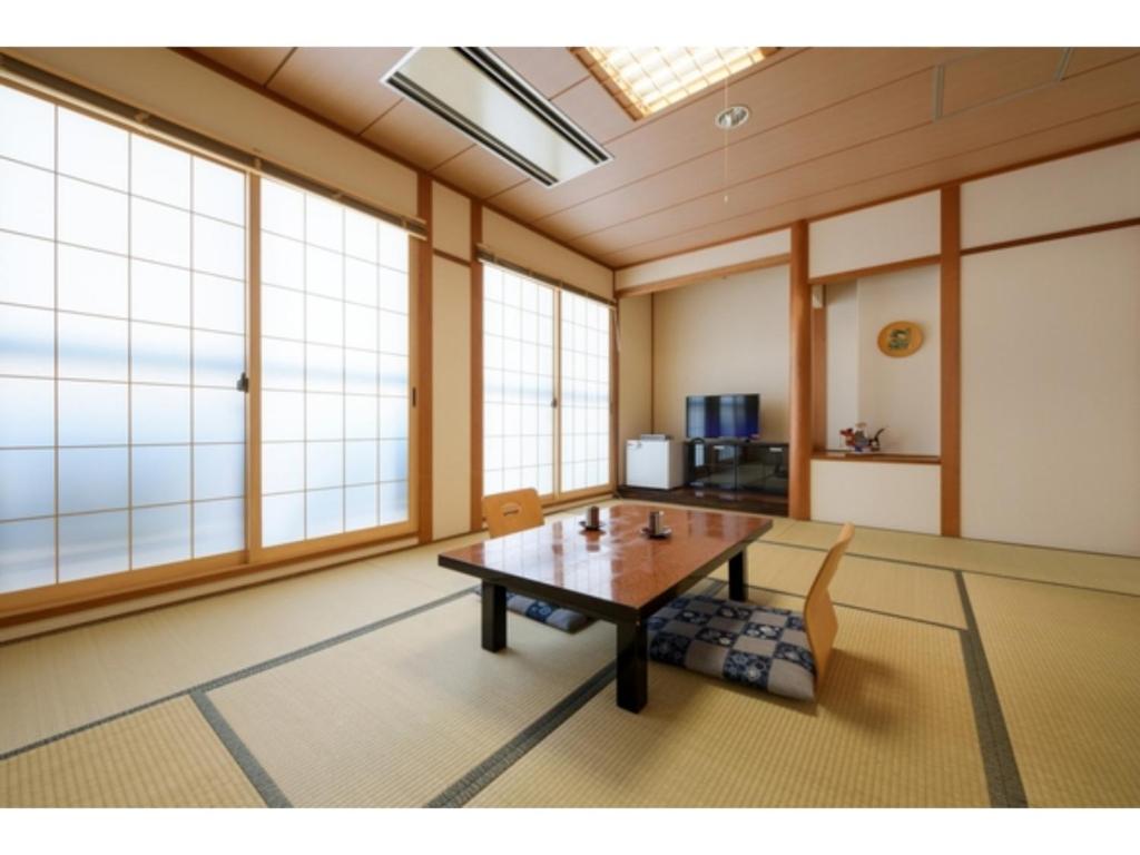 um quarto com uma mesa, cadeiras e janelas em Towada City Hotel - Vacation STAY 47310v em Towada