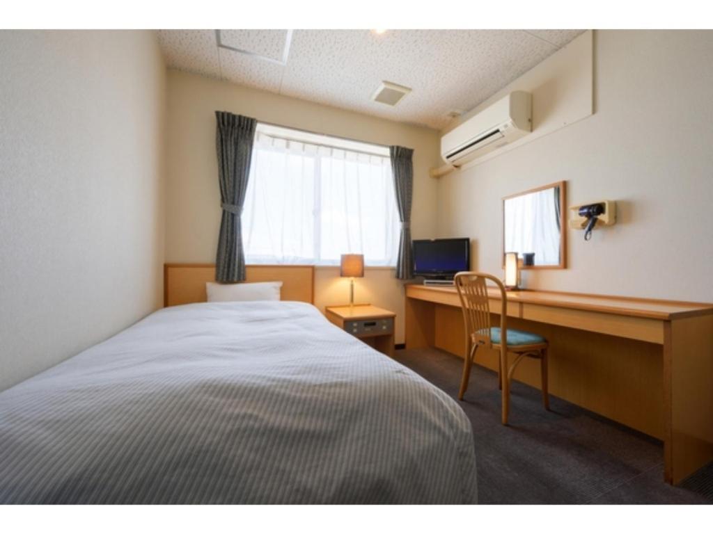 ein Schlafzimmer mit einem Bett und einem Schreibtisch mit einem Computer in der Unterkunft Towada City Hotel - Vacation STAY 47295v in Towada