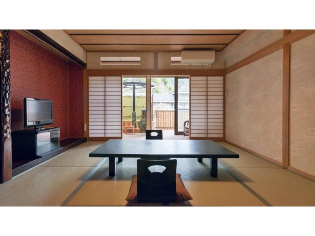 Myoken Onsen Nemu - Vacation STAY 20783v في كيريشيما: غرفة معيشة مع طاولة وتلفزيون