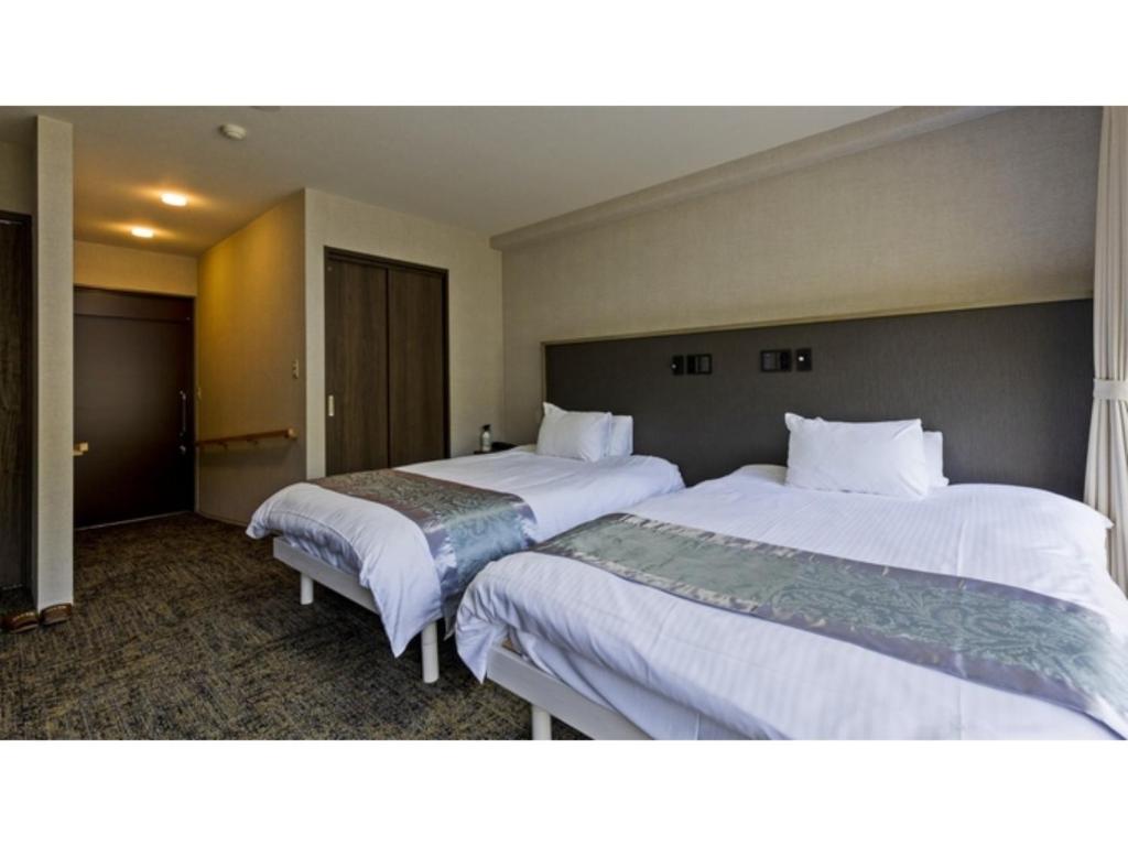 Myoken Onsen Nemu - Vacation STAY 20873v في كيريشيما: سريرين في غرفة الفندق ذات شراشف بيضاء