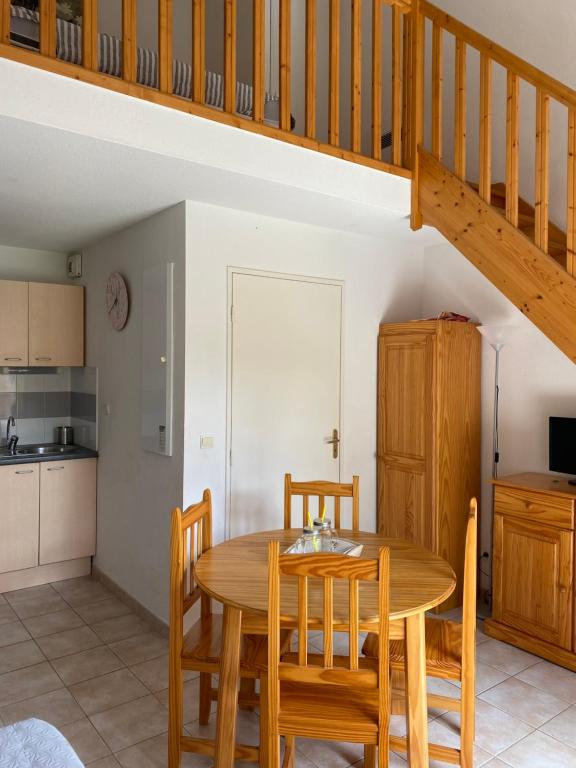 une cuisine et une salle à manger avec une table et des chaises en bois dans l'établissement Maison résidence Odalys, à Calvisson
