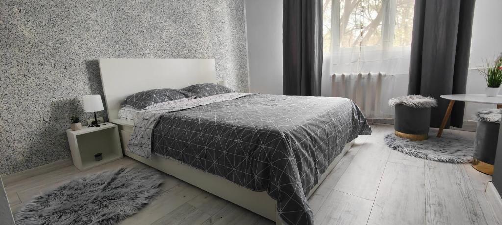 ein Schlafzimmer mit einem Bett mit einer grauen Decke und einem Fenster in der Unterkunft Residence Angelina in Arad