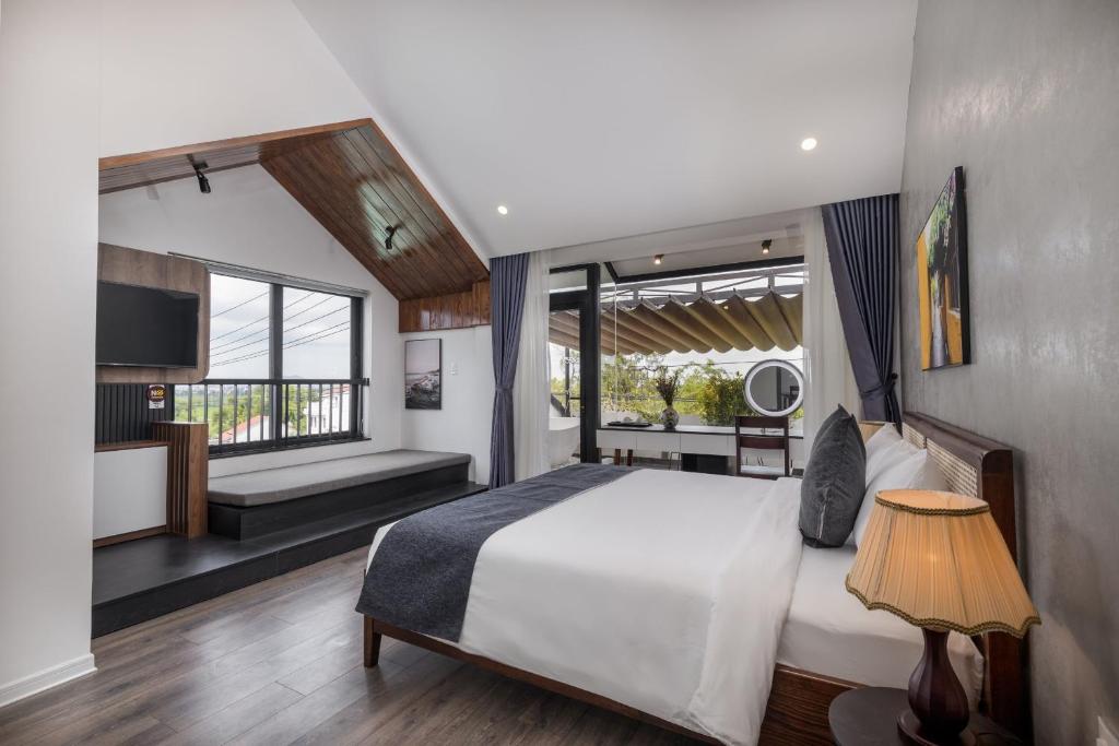 a bedroom with a white bed and a large window at Charm Champion Villa Hoian in Hoi An