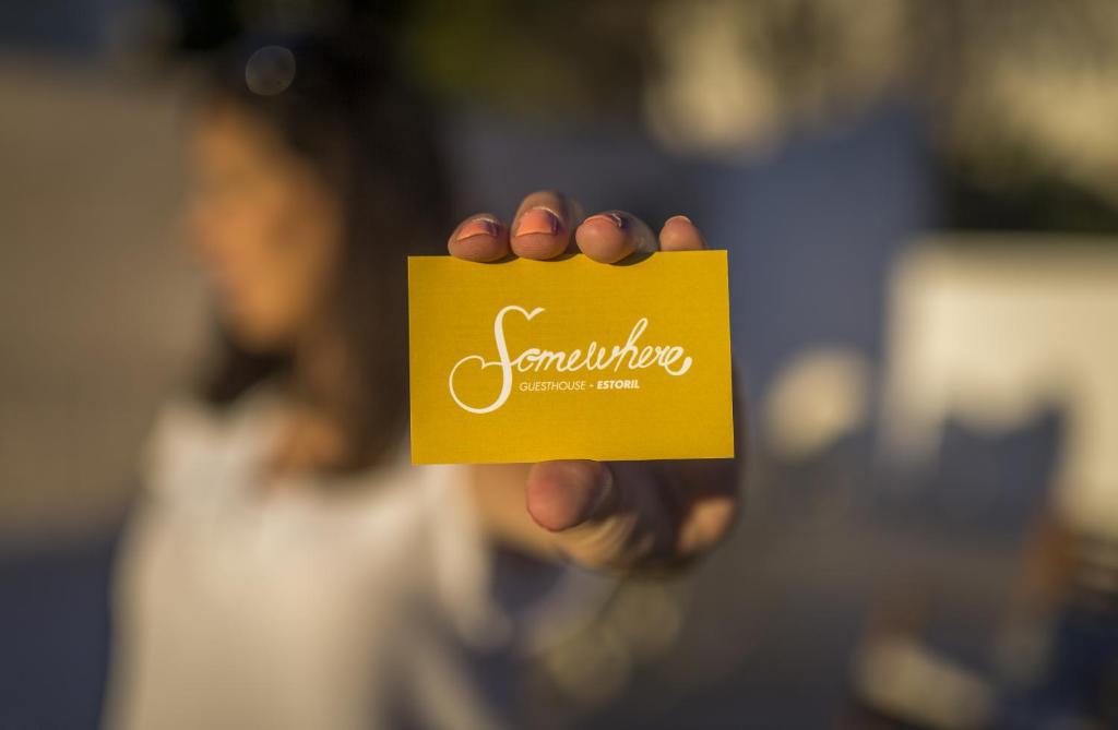 a hand holding a yellow sign with the word volunteering at Somewhere - Estoril Guesthouse in Estoril