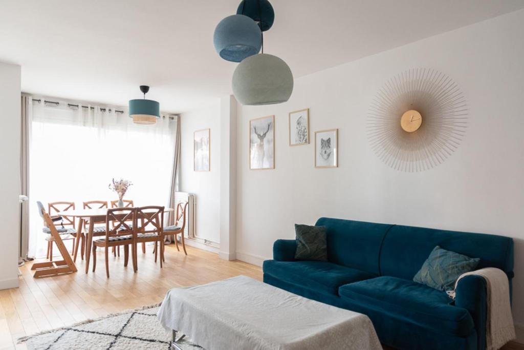 een woonkamer met een blauwe bank en een tafel bij Spacious nest just outside Paris in Levallois-Perret