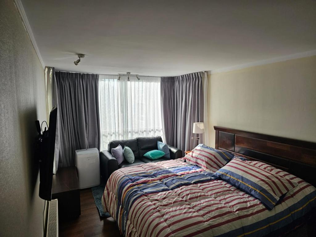 um quarto com uma cama e um sofá ao lado de uma janela em Refugio IDEAL em Santiago